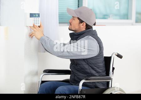 male electrician installing security system door sensor on wall Stock Photo