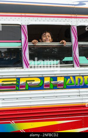 A young Panamanian boy smiles from the window of a Red Devil bus in Portobelo, Panama.  The Diablos Rojos or Red Devils are a common form of public tr Stock Photo