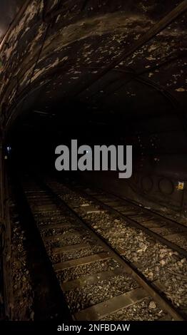 Barcelona metro rails, underground track inside the tunnel with a metro car approaching from the background. Low light. Stock Photo