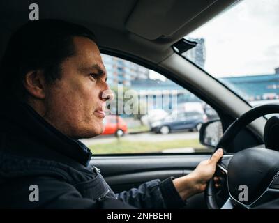 Portrait of stressed male driver driving car with serious expression. Stock Photo