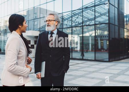 Senior business man talking to his secretary outside of the office building Stock Photo