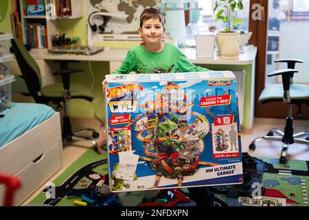 Ternopil, Ukraine - February, 2023: Boy unboxing Hot Wheels City Ultimate Garage, play in children room. Stock Photo