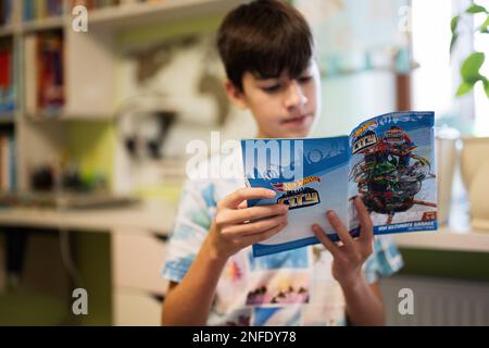 Ternopil, Ukraine - February, 2023: Boy reads the instructions for use Hot Wheels Ultimate Garage, play in children room. Stock Photo