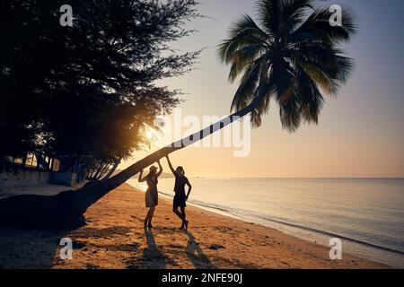 Happy couple in silhouette on the tropical beach near palm tree of Phi Phi island in Southern Thailand. Travel magazine vacation concept. Stock Photo
