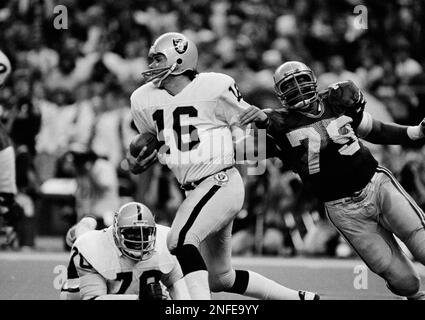 Los Angeles running back Marcus Allen (32) tries to break away from  Washington Redskins Dave Butz (65) as Rich Milot (57) looks on during the  first half of their game at R.F.K.