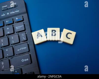Black keyboard and toy word with the word ABC on blue background. Education concept. Stock Photo