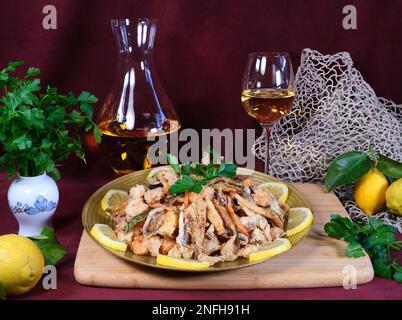 Fried mixed fish from the Adriatic Sea such as cuttlefish, prawns, squid, anchovies. There are courgettes, carrots, fried mushrooms and lemon. Stock Photo