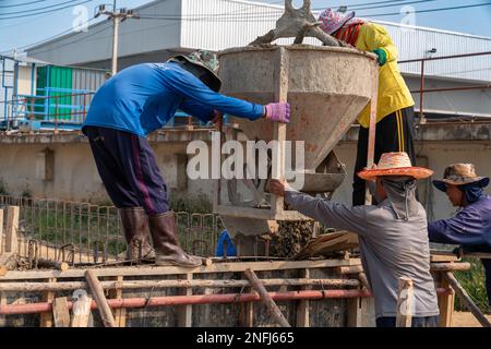 Workers during concrete pouring into formwork at construction site. Stock Photo
