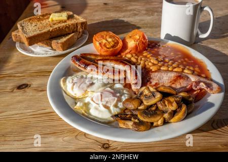Traditional Full English Breakfast with Eggs, Bacon, Sausage, and Baked Beans Stock Photo