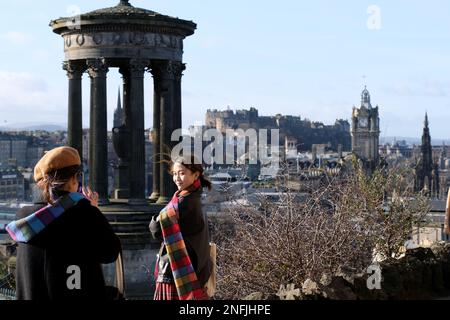 Edinburgh, Scotland, UK. 17th February 2023. Visitors on Calton hill wrapped up against the cold blustery winds. Visitors Taking a selfie with a view of Edinburgh Castle. Credit: Craig Brown/Alamy Live News Stock Photo