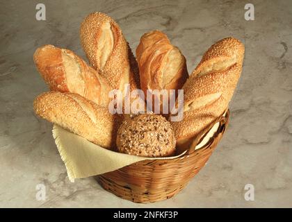Various types of bread in a basket in a wicker basket on a marble background. Stock Photo
