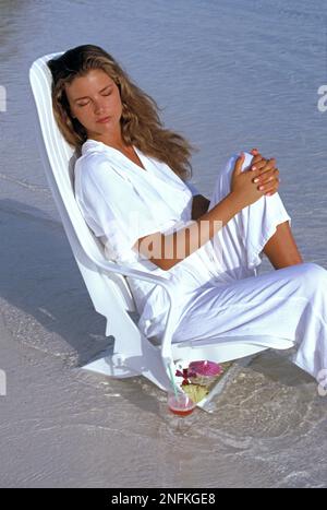 Maldives. Young woman relaxing on chair on tropical beach. Stock Photo