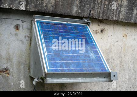 Stationary small solar panel on a concrete wall. Stock Photo