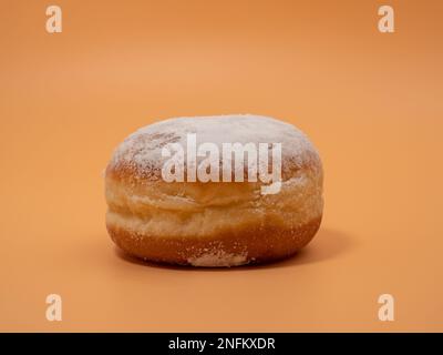 Freshly baked and dusted with powdered sugar German donuts. Donut berliner or krapfen on orange background. Stock Photo