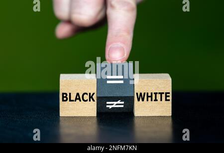 Symbol for equal rights of persons with different skin colors. Hand turns wooden cube and changes the unequal sign to a equal sign. Stock Photo