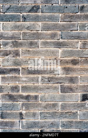 A plain brick wall background with multi-colored bricks ranging from black to light brown Stock Photo