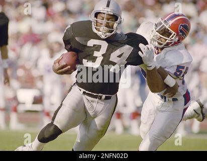 Los Angeles Raiders running back Bo Jackson (34) carries the ball after  taking handoff from quarterback Jay Schroeder (13) against the Kansas City  Chiefs, Sunday, Nov. 25, 1990, in Los Angeles. The