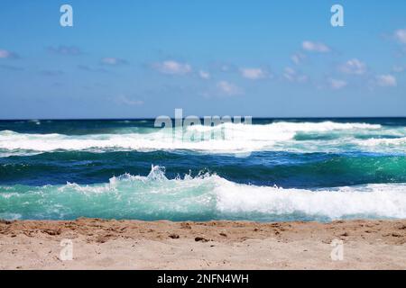 View of waves on the sea and empty sandy beach close-up. Stock Photo