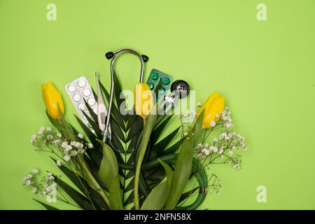 Bouquet of flowers and stethoscope on a green background, a place for text, happy doctors day, nurses week and other medical holidays. Stock Photo