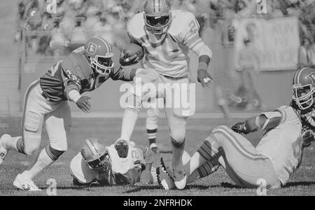 Denver Broncos defender Billy Thompson reaches for Detroit Lions running  back Billy Sims (20) on Oct. 11, 1981 in Denver, as Sims steps over two of  his players on his way to