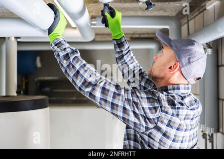 Professional Plumber Checking Water Valves in the Pipes of the Residential House Heating System. Stock Photo