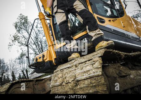 Industrial Excavator Operator Standing on the Crawler Track. Heavy Duty Construction Machinery Theme. Stock Photo