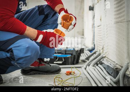 Caucasian Electrician Assembling Electrical Boxes During Wiring System Installation in Newly Built Apartment. Stock Photo