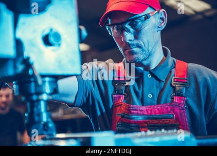 Professional Caucasian CNC Milling Machine Operator Focused on Cutting Process in His Workshop. Industrial Technology Theme. Stock Photo