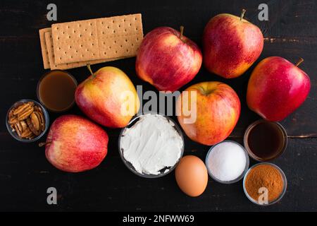 Cheesecake Stuffed Apple Ingredients on a Wooden Table: Gala apples, cream cheese, and other ingredients on a dark wood background Stock Photo