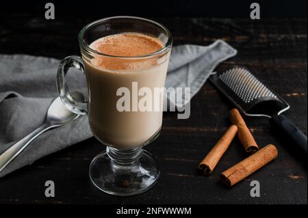 Cozy Almond Rooibos Tea Latte Topped with Cinnamon: A glass mug filled with a tea latte and garnished with sprinkled cinnamon Stock Photo