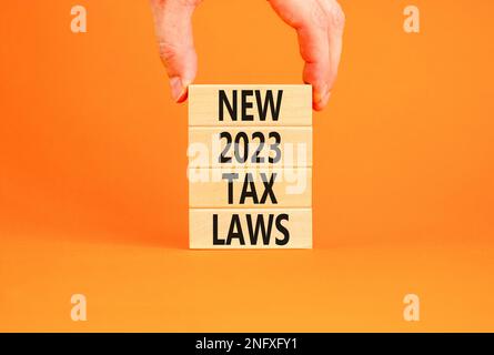 New 2023 tax laws symbol. Concept words New 2023 tax laws on wooden blocks. Beautiful orange table orange background. Businessman hand. Business new 2 Stock Photo