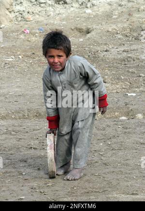 A barefoot Afghan boy plays at the Shin Ghazi Baba refugee camp on