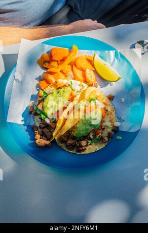 Two tacos at outdoor restaurant on blue plate with lime wedge and pickle carrots (escabeche) Stock Photo