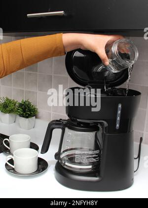 Woman's hands prepare delicious and aromatic coffee in coffee maker in the kitchen for breakfast with water and freshly ground coffee Stock Photo