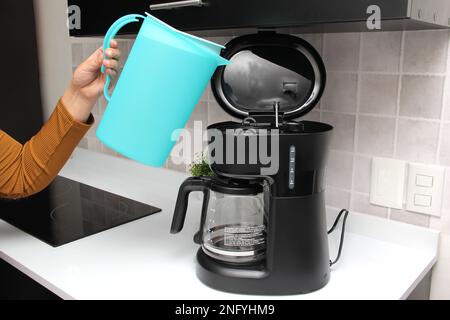 Woman's hands prepare delicious and aromatic coffee in coffee maker in the kitchen for breakfast with water and freshly ground coffee Stock Photo