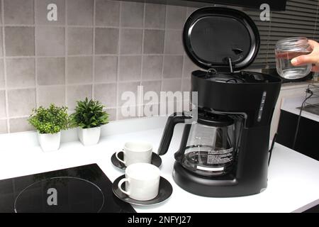 Woman's hands prepare delicious and aromatic coffee in coffee maker in the kitchen for breakfast with water and freshly ground coffee Stock Photo