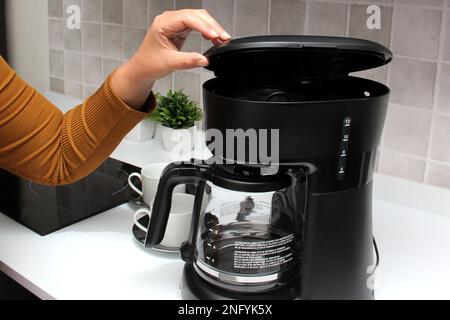 Woman's hands prepare delicious and aromatic coffee in coffee maker in the kitchen for breakfast with water and freshly ground coffee Stock Photo