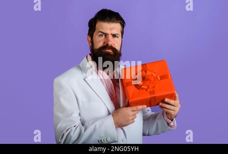Bearded man with gift box. Businessman with present gift box. Handsome guy with present box. Womens or Mothers Day celebration. Male with birthday Stock Photo