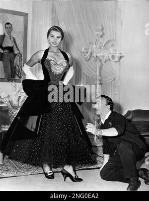 Italian actress Sophia Loren tries one of a set of evening dresses