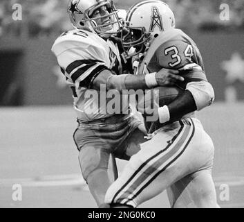 Dallas Cowboys' safety Randy Hughes (42) wrestles with Houston Oilers' star  running back Earl Campbell (34) in Saturday night, Aug. 24, 1980 exhibition  game at Texas Stadium. Campbell picked up a first down on the play before  being stopped by Hughes