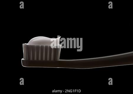 Close up of white toothbrush with toothpaste isolated on black background Stock Photo