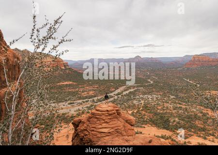 Woman hiker standing on Bell Rock with incredible views within coconino national forest in Sedona Arizona USA against white cloud background. Stock Photo