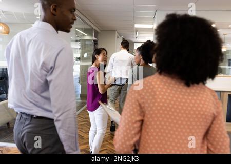 Back view of diverse businesspeople walking and talking in office Stock Photo