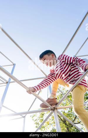 A young boy climbs up in a public playground. It was in Daan public park in Taipei, Taiwan. Stock Photo