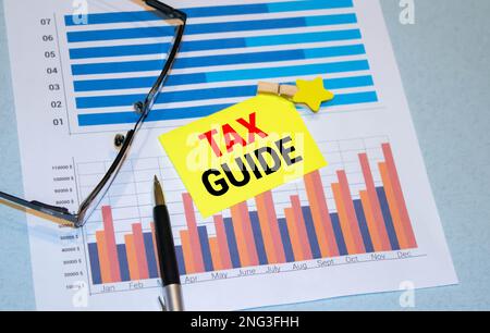 yellow card with text TAX GUIDE on tax forms. Stock Photo