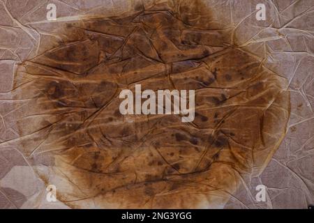 Textured dirty wrinkled brown old paper background with a large spot in the center. Horizontal background for design, closeup Stock Photo