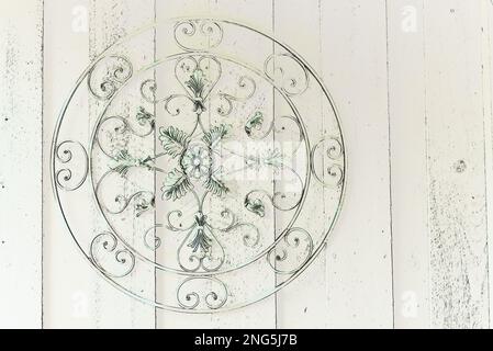 Round scrolled metal piece hanging on wooden wall with copy space Stock Photo