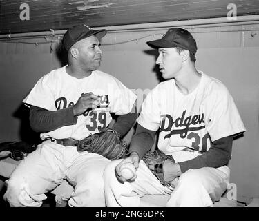 Dodgers catcher Roy Campanella, center, tosses aside his mask as