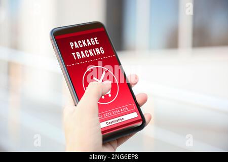 Woman tracking parcel via smartphone outdoors, closeup Stock Photo