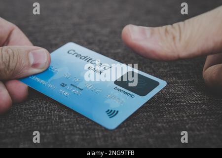Close up of male hands holding credit card with fingerprint scanner and embedding the thumb to pay online. Concept of using biometric technology in ba Stock Photo